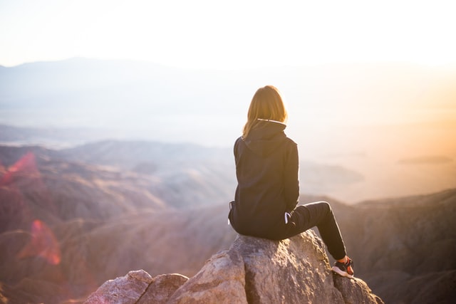 person sitting on mountaintop at sunset